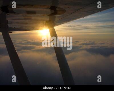 Vista aerea del tramonto sotto l'ala di un velivolo leggero (Piper PA18 Super Cub), cieli britannici Foto Stock