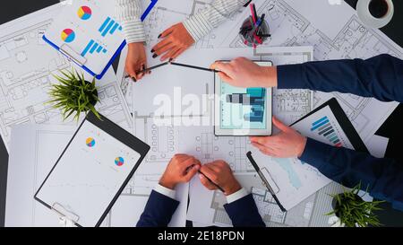 Vista dall'alto di architetti e interior designer che si riuniscono ispezionando e concludendo con il progetto di ristrutturazione del cambiamento. I progettisti si avvalorano di un moderno concetto di dispositivo su spazio di copia e di posa piatta Foto Stock