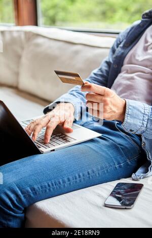 Sezione centrale dell'uomo adulto medio che effettua il pagamento in linea Foto Stock