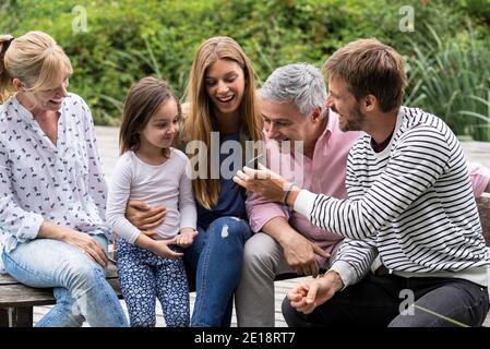 La famiglia guarda lo smartphone Foto Stock