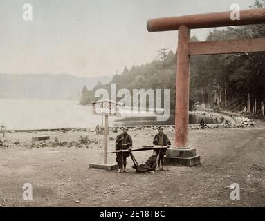 Fotografia d'epoca del XIX secolo - epoca Meiji Giappone: torri, sedia da trasporto, sedia berlina, sulla riva del lago Hakone. Foto Stock