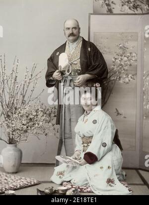 Fotografia d'epoca del XIX secolo - epoca Meiji Giappone: Ritratto di una coppia occidentale vestita di abiti giapponesi in un ambiente stduio, probabilmente turisti. Foto Stock