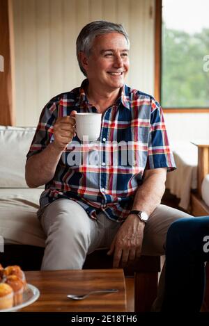 Uomo anziano sorridente che ha caffè Foto Stock