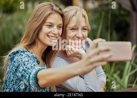 Donna con la madre in legge che prende selfie Foto Stock