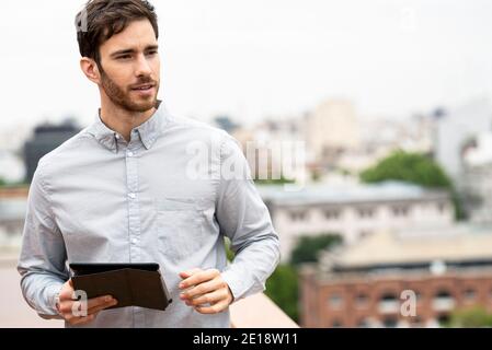 Giovane uomo in piedi all'aperto con tablet digitale Foto Stock