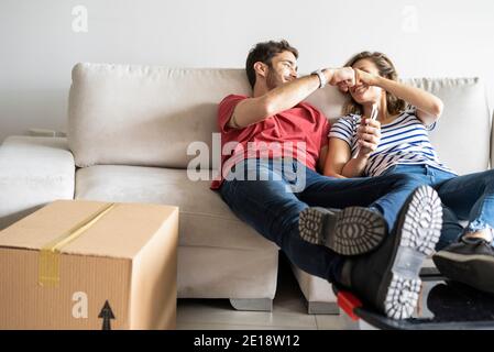 Una giovane coppia sorridente che si rilassa sul divano nella sua nuova casa Foto Stock