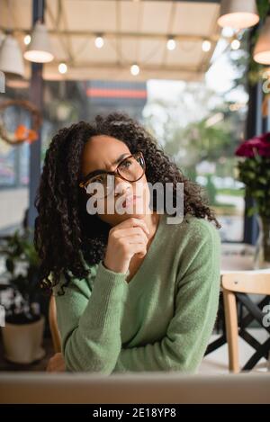 donna afro-americana pensierosa in occhiali che guardano via Foto Stock
