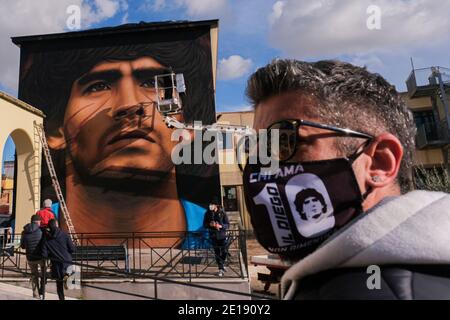 Napoli, Italia. 4 gennaio 2021. Luigi un ragazzo locale indossa una maschera per contenere l'infezione da COVID-19 raffigurante Maradona nella piazza per ammirare il nuovo murale Jorit Agoch Street artist di Napoli, Crea il suo nuovo murale in quarto in provincia di Napoli il volto di Diego Armando Maradona morì il 25 novembre 2020, Dique Luján, Argentina, ex giocatore del ssc napoli dal 1984 al 1991. La figura di maradona a napoli e la provincia è venerata come un santo. Credit: Agenzia fotografica indipendente/Alamy Live News Foto Stock