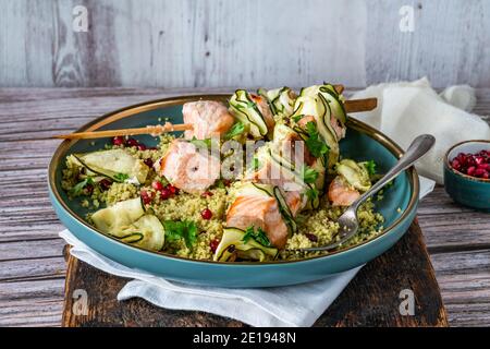 Spiedini di salmone e zucchine con couscous al limone e semi di melograno Foto Stock