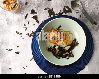 Gli spaghetti alle alghe kombu in un piatto blu Foto Stock