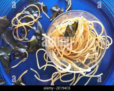 Gli spaghetti alle alghe kombu in un piatto blu Foto Stock