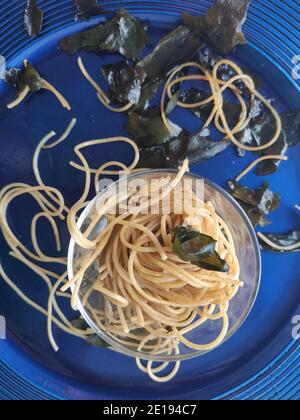 Gli spaghetti alle alghe kombu in un piatto blu Foto Stock