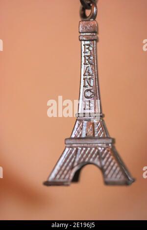 Portachiavi in metallo sotto forma di Torre Eiffel a Parigi, Francia. Souvenir del primo piano del viaggio su sfondo arancione Foto Stock