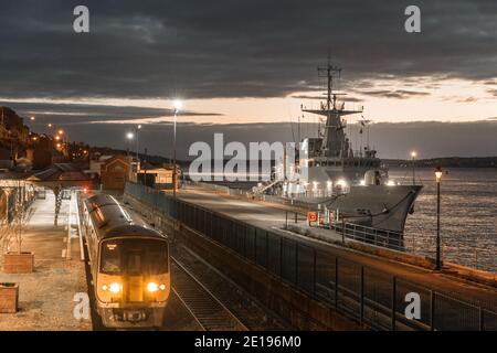 Cobh, Cork, Irlanda. 05 gennaio 2021. Nave navale irlandese LÉ George Bernard Shaw all'ormeggio di acque profonde prima dell'alba, come un treno di mattina presto lascia la stazione a Cobh, Co. Cork, Irlanda. - credito; David Creedon / Alamy Live News Foto Stock