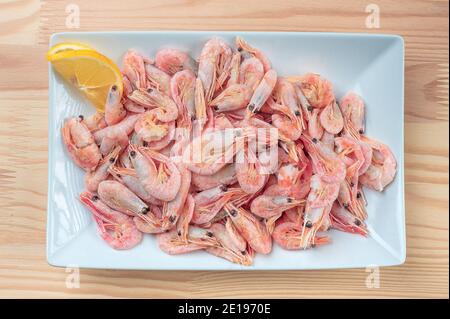 Gamberetti bolliti con limone su un piatto bianco. Gamberetti cotti freschi in piatto bianco con limone. Primo piano di gamberi bolliti freschi in piastra bianca. Vista dall'alto Foto Stock