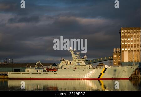 MPV Jura, nave di protezione marina per la pesca del governo scozzese e silo di grano industriale con riflessi, Imperial Dock, Leith, Edimburgo, Scozia, Regno Unito Foto Stock