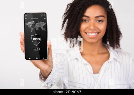 Donna nera che tiene in mano e mostra lo smartphone con l'app vpn Foto Stock