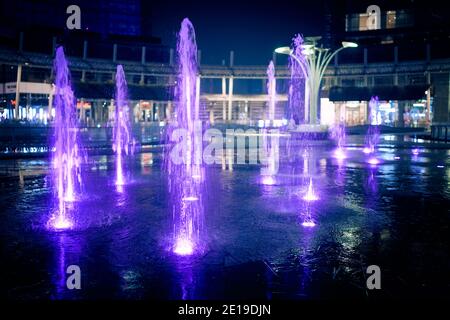 Fontane d'acqua illuminate in piazza Gae Aulenti circondate da moderni grattacieli. Quartiere di porta Garibaldi. Milano, Italia - Dicembre 17 Foto Stock