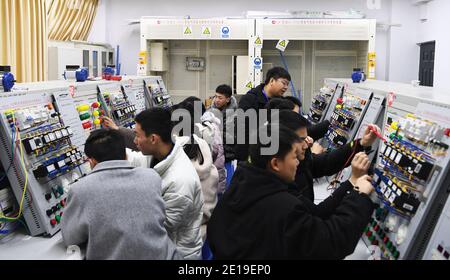 (210105) -- CHONGQING, 5 gennaio 2021 (Xinhua) -- Liang Pan insegna gli studenti al Chongqing Technician College of Railway Transportation nel sud-ovest della Cina Chongqing, 30 dicembre 2020. Liang Pan, che una volta ha fallito l'esame di ingresso della scuola superiore, ora è un insegnante al Chongqing Technician College of Railway Transportation. Da uno studente di scuola professionale secondaria, un laico di elettronica ad un esperto e campione del mondo, Liang Pan ha impiegato 6 anni per realizzare il sogno. Le esperienze lavorative in giovane età hanno fatto di Liang Pan capire l'importanza di padroneggiare un'abilità e di amare la o Foto Stock