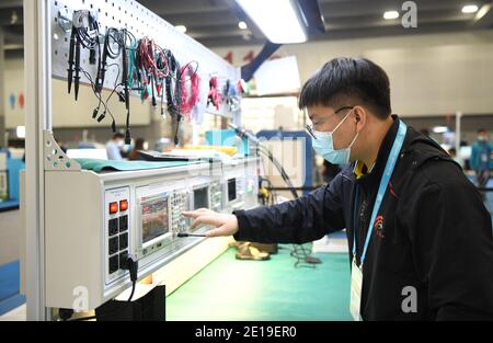 (210105) -- CHONGQING, 5 gennaio 2021 (Xinhua) -- Liang Pan lavora come assistente all'arbitro di elettronica alla prima competizione nazionale di abilità professionali a Guangzhou, provincia di Guangdong del sud della Cina, 10 dicembre 2020. Liang Pan, che una volta ha fallito l'esame di ingresso della scuola superiore, ora è un insegnante al Chongqing Technician College of Railway Transportation. Da uno studente di scuola professionale secondaria, un laico di elettronica ad un esperto e campione del mondo, Liang Pan ha impiegato 6 anni per realizzare il sogno. Le esperienze lavorative in giovane età hanno fatto di Liang Pan realizzare l'impatto Foto Stock