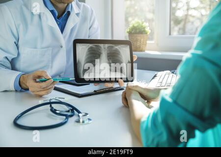 il medico e il paziente discutono i risultati della radiografia toracica su tablet digitale in ambulatori Foto Stock