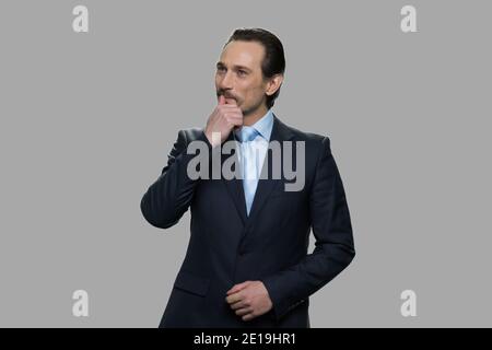 Uomo d'affari maturo che sogna daydreaming su sfondo grigio. Foto Stock