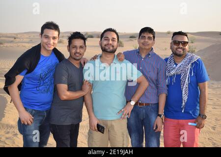 10 febbraio 2017. Dubai, Emirati Arabi Uniti. Giovani amici guardando la macchina fotografica nel deserto durante il tramonto, gli amici si riunirono chiacchierando. Foto Stock