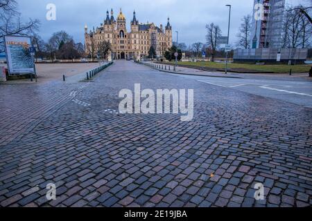 Schwerin, Germania. 05 gennaio 2021. Il castello di Schwerin si trova dietro la strada principale vuota della capitale dello stato. Il Cancelliere e i Presidenti dei Ministri degli stati federali stanno discutendo di un ampliamento della chiusura per contenere la pandemia di Corona. Credit: Jens Büttner/dpa-Zentralbild/dpa/Alamy Live News Foto Stock