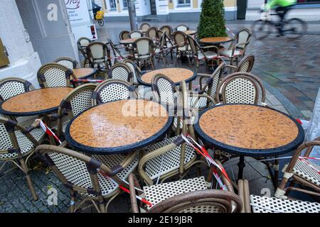 Schwerin, Germania. 05 gennaio 2021. Un ciclista passa accanto a tavoli assemblati in un bar sul marciapiede nel centro della città, quasi desertato. Il cancelliere tedesco e i presidenti dei ministri degli stati tedeschi discutono di un'estensione del blocco per contenere la pandemia di Corona. Credit: Jens Büttner/dpa-Zentralbild/dpa/Alamy Live News Foto Stock