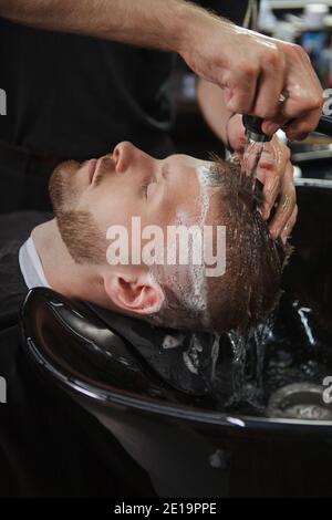 Primo piano verticale di un uomo che ha i suoi capelli lavati da barbiere professionista Foto Stock