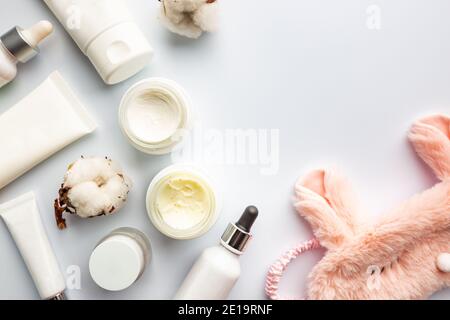 Contenitori bianchi cosmetici con maschera di sonno su sfondo bianco vista dall'alto. Prodotti per la cura notturna della pelle. Vaso crema idratante per mani, viso e corpo. Foto Stock