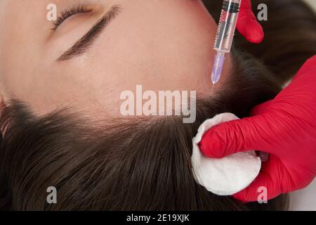 Il medico di bellezza fa acido ialuronico ringiovanimento iniezioni di bellezza in testa di bella giovane paziente femminile per la crescita dei capelli e a. evitare il coraggio Foto Stock