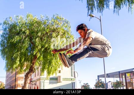 Giovane latino attivo che salta in azione. Attività sportive estreme, parkour all'aperto, corsa libera o concetto di stile di vita sano Foto Stock