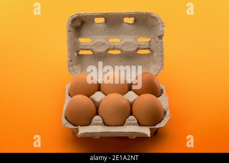 Scatola di uova con uova, sei uova di pollo in cartone vassoio di uova fatto di carta riciclata isolato su sfondo giallo arancio Foto Stock