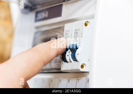 La mano punta a un fusibile nel misuratore di potenza. L'uomo disabilita i fusibili di corrente, il concetto di sicurezza della soppressione di potenza e la protezione di e. Foto Stock