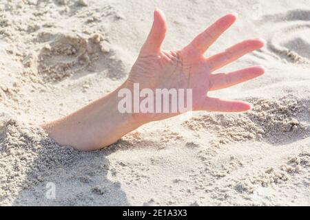 Primo piano della mano. Mani sepolte in sabbia su una spiaggia Foto Stock