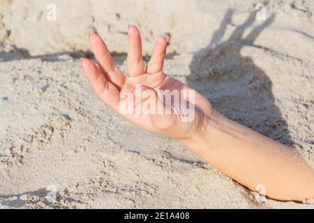 Primo piano della mano. Mani sepolte in sabbia su una spiaggia Foto Stock