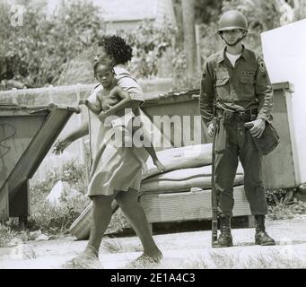 1968 rivolte di Liberty City. La Guardia Nazionale della Florida è stata chiamata ad aiutare a sedare la violenza. Qui una donna porta il suo bambino davanti a un guardiano nazionale. Miami, Florida. Foto Stock