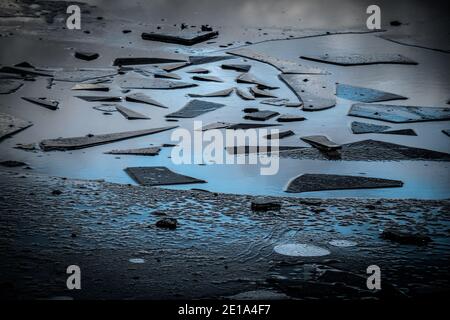 Ghiaccio rotto su puddle, Inghilterra in inverno. Modello astratto. Foto Stock