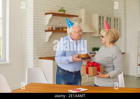 Felice coppia anziana in vacanza cappelli preparazione per festa di compleanno a casa Foto Stock