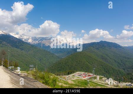 Sochi Krasnaya Polyana nella primavera del 29 aprile 2018. Vista delle montagne innevate, delle nuvole e dei siti turistici. Verde primavera foresta sulle pendici di Foto Stock