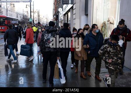 Scena di acquirenti che fanno un po' di shopping natalizio dell'ultimo minuto lungo Oxford Street, mentre il primo ministro annuncia un nuovo più stretto quarto livello di restrizioni locali al coronavirus per Londra e il Sud-est, E che il previsto rilassamento natalizio delle regole doveva essere demolito il 19 dicembre 2020 a Londra, Regno Unito. Questi acquirenti, per lo più indossando maschere facciali erano ignari, così come i proprietari di negozi che le nuove regole stavano per essere annunciate, e questo significherebbe che tutti i negozi non essenziali dovranno chiudere a partire da mezzanotte. Foto Stock