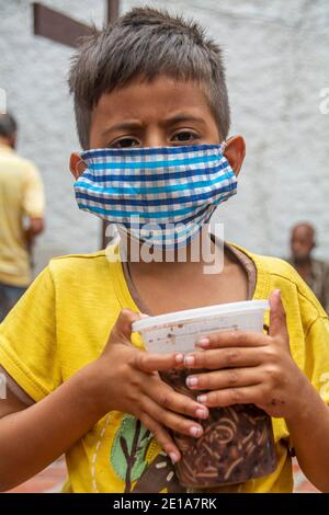 Un bambino è felice dopo aver ricevuto il suo piatto di cibo, attraverso il piatto di solidarietà. Attraverso un sistema di numerazione, a tutte le persone che necessitano di cibo viene dato un numero Foto Stock