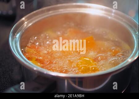 Bollire patate e patate in una pentola in acciaio inox con vapore che sale. Foto Stock