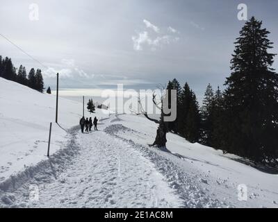 persone che camminano su un sentiero tra le montagne innevate Foto Stock