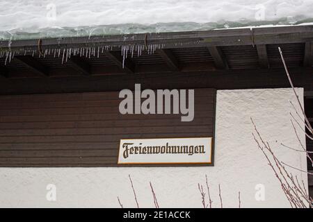 tetto coperto di neve di un fienile con ghiaccio sul grondaia Foto Stock