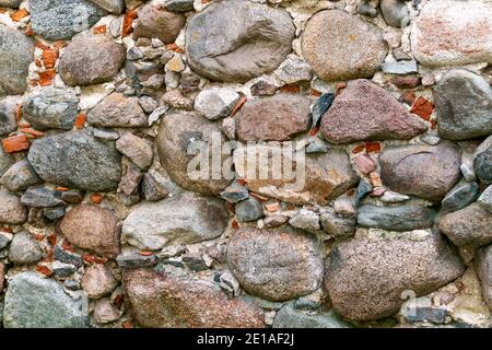 Vecchio muro di muratura di grandi ciottoli di granito. Foto Stock