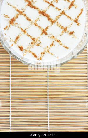 Budino di riso cremoso alla cannella su tappetino di paglia di bambù come sfondo Foto Stock