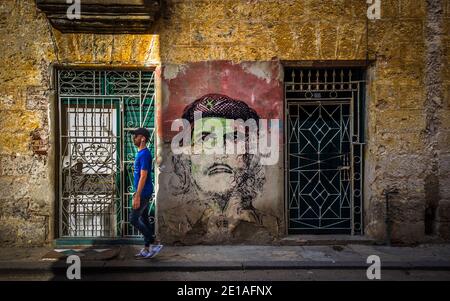 L'Avana, Cuba, 2019 luglio, uomo che cammina per un murale tra due porte di che Guevara nella parte più antica della capitale Foto Stock