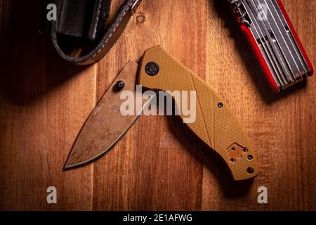 coltello pieghevole su una superficie di legno con accessori Foto Stock